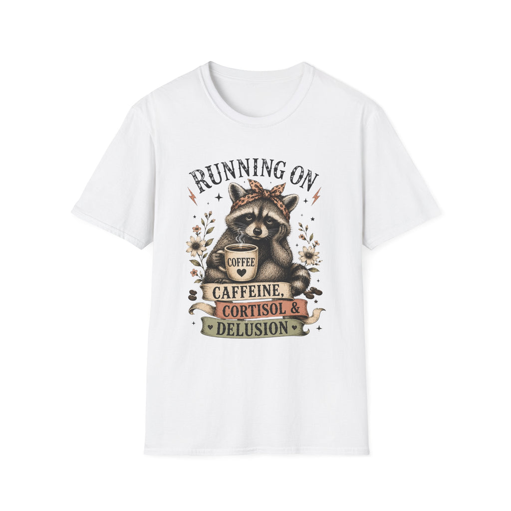 A white short-sleeve crewneck t-shirt featuring a graphic print of a raccoon wearing a crown and holding a coffee mug, surrounded by the text 'RUNNING ON CAFFEINE, CORTISOL & DELUSION'.