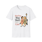 A white short-sleeve crewneck t-shirt featuring a retro graphic of two young girls walking side-by-side next to a vintage street lamp, with the text 'Matching Mug Shots Would Be Cute' printed above them.