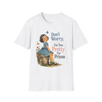 A white short-sleeve crewneck t-shirt featuring a vintage-style graphic of a young girl in a blue dress sitting on a stone, surrounded by flowers and butterflies, with the text 'Don't Worry. I'm Too Pretty For Prison' printed on the front.