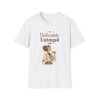A white short-sleeve crewneck t-shirt featuring a vintage-style graphic print on the front. The graphic displays the text 'Delicately Unhinged' in a dusty rose and black font, above an illustration of a woman in a 1920s flapper outfit.