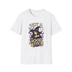 A white short-sleeve crewneck t-shirt featuring a graphic print of a witch with the text 'NOT A GOOD WITCH' in a stylized font, accompanied by purple smoke, a crescent moon, and bats.