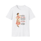 A white short-sleeve crewneck t-shirt featuring a retro-style graphic of a pin-up woman in a pink dress next to the text 'YOU'RE ONE MORE SENTENCE AWAY FROM BECOMING A STORY'.