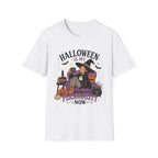 A white short-sleeve crewneck t-shirt featuring a colorful Halloween-themed graphic print on the front. The graphic shows a witch sitting on a purple couch with a striped cat, surrounded by pumpkins, a cauldron, and bats, with the text 'HALLOWEEN IS MY PERSONALITY NOW'.