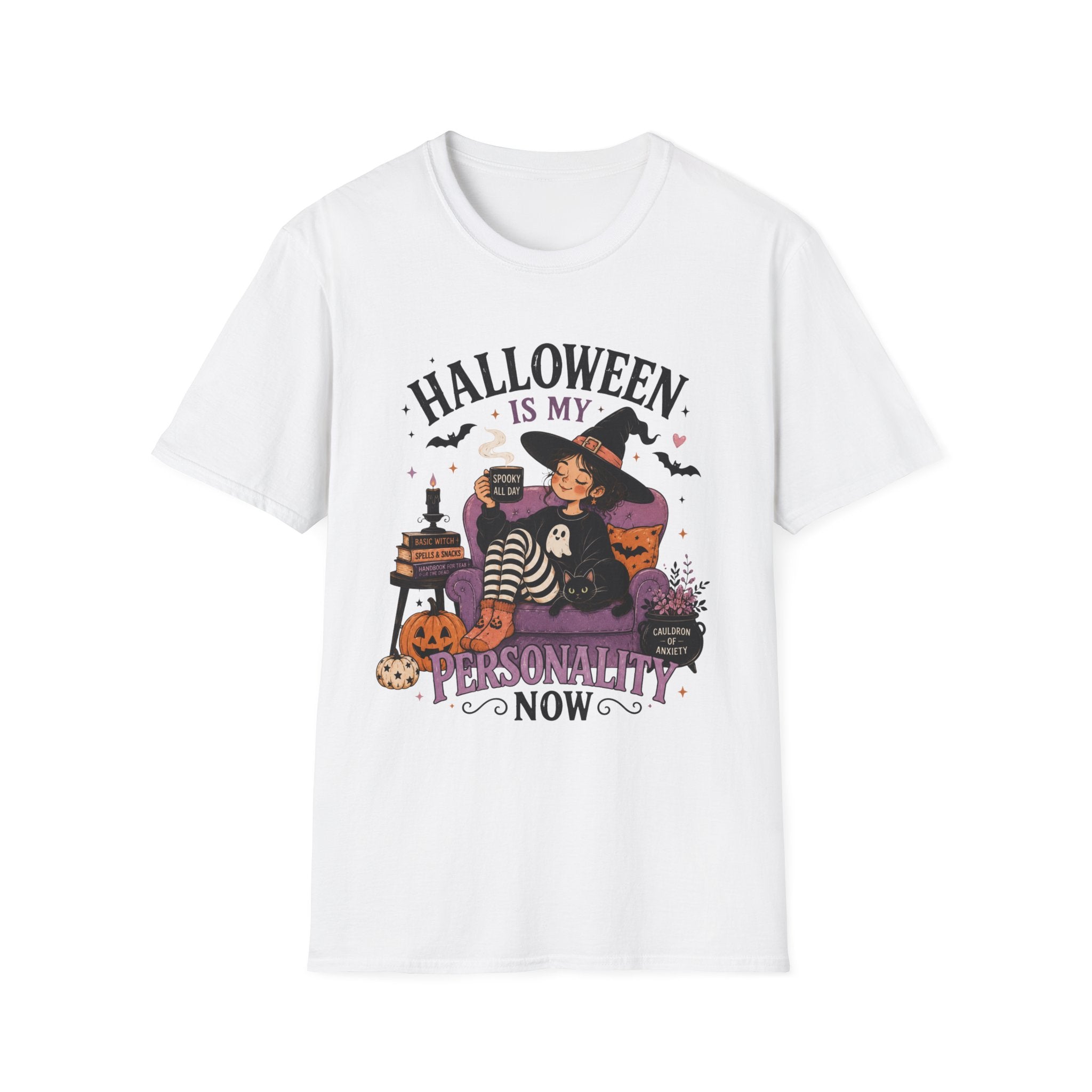 A white short-sleeve crewneck t-shirt featuring a colorful Halloween-themed graphic print on the front. The graphic shows a witch sitting on a purple couch with a striped cat, surrounded by pumpkins, a cauldron, and bats, with the text 'HALLOWEEN IS MY PERSONALITY NOW'.