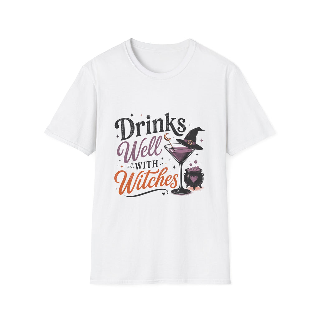 A white short-sleeve crewneck t-shirt featuring a Halloween-themed graphic print on the front that reads 'Drinks Well WITH Witches' in stylized black, purple, and orange lettering, accompanied by illustrations of a witch hat, a martini glass, and a cauldron.